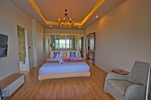 een slaapkamer met een groot bed en een stoel bij 无边泳池海景别墅 in Phuket