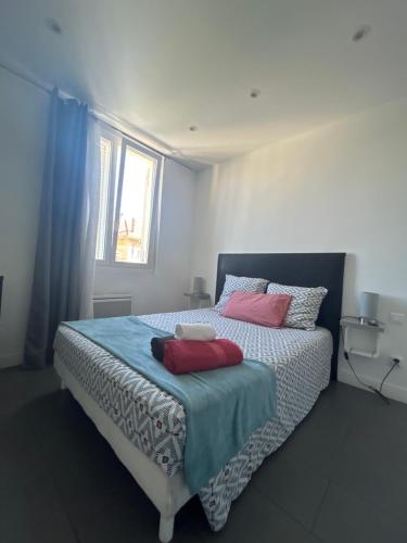 une chambre avec un lit avec des oreillers rouges et une fenêtre dans l'établissement L'ensoleillée Appartement Maison privé Cannes, à Cannes