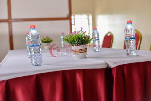 two bottles of water sitting on a table with flowers at Heritage Villa Hotel & Accomodation in Kericho