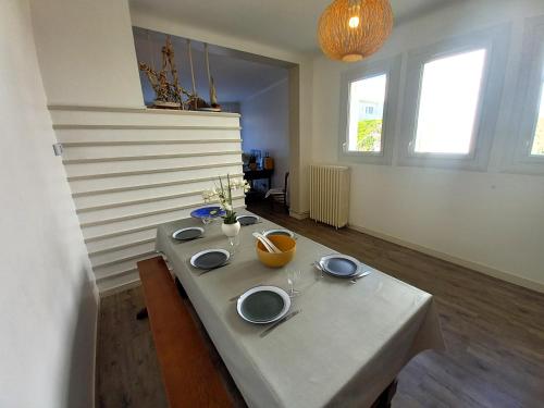 - une table avec des assiettes dans une pièce dans l'établissement Royan - MAISON des années 50 RENOVEE à proximité de la PLAGE de FONCILLON, à Royan