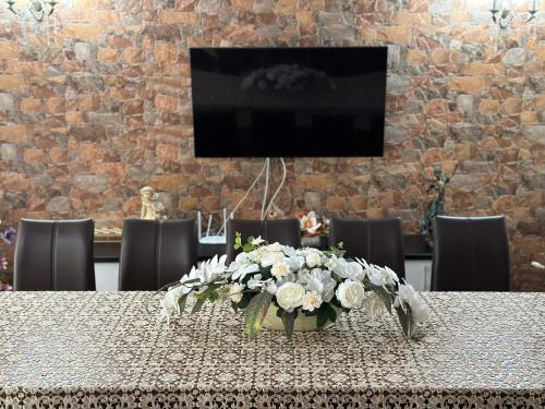 a vase of flowers on a table with a tv at Casa Antonia in Chişcău