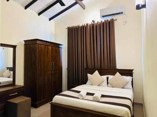 a bedroom with a large bed with a dresser and a mirror at Viveka Serviced Apartments in Nugegoda
