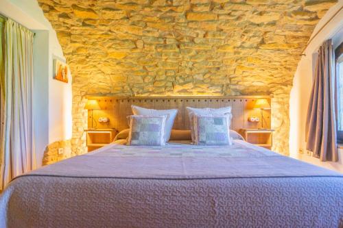 a bedroom with a large bed with a stone wall at Hotel Mas Rabiol -Costa Brava-Emporda-Only Adults in Peratallada