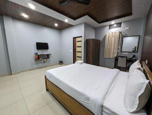 a bedroom with a large bed and a flat screen tv at HOTEL ENCANTO IMPHAL in Imphal