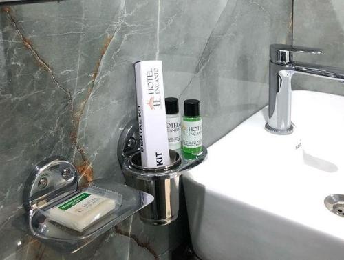 łazienka z umywalką i zestawem kosmetyków na ladzie w obiekcie HOTEL ENCANTO IMPHAL w mieście Imphal