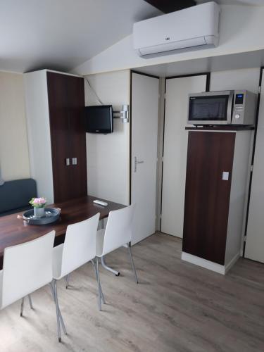 Cette chambre dispose d'une table, de chaises et d'un four micro-ondes. dans l'établissement Camping du phare d opale p48, à Le Portel