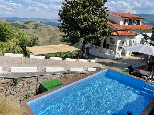 uma grande piscina azul em frente a uma casa em Villa Samaritana - Casa da Vinha em Vila Marim