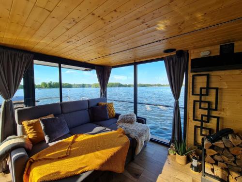 a couch in a room with a view of the water at Seezeit im Hausboot mit Kamin & Sauna in Müllrose