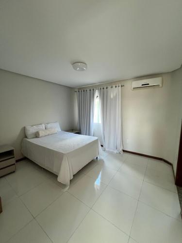 a bedroom with a white bed and a window at Casa com 4 suítes, todas as suítes com ar condicio in Vitória da Conquista