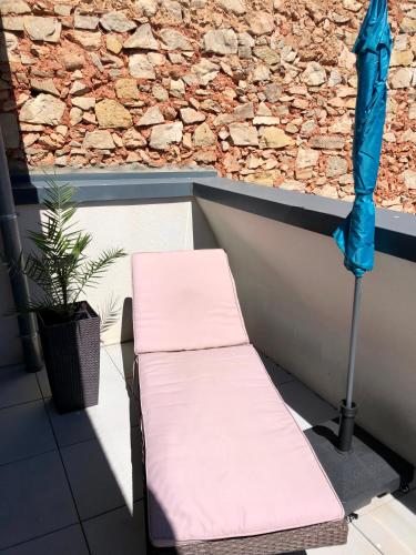 un banc et un parasol sur un balcon dans l'établissement Duplex Jaden - 3 pièces climatisé 80m2, à Villeveyrac