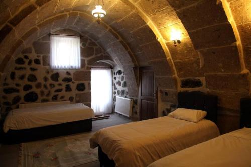 a bedroom with two beds in a stone building at Burhan bey konagı in Aksaray