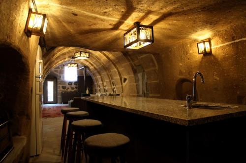 a bar with stools in a room with a stone wall at Burhan bey konagı in Aksaray
