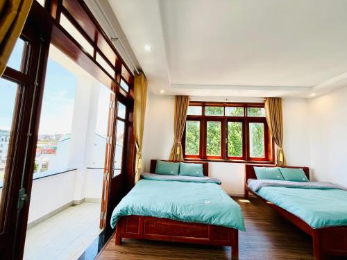 two beds in a room with two windows at NHỚ House Đà Lạt V in Da Lat
