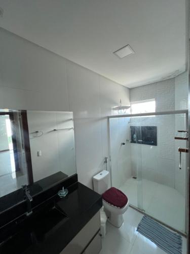 uma casa de banho com uma cabina de duche em vidro e um WC. em Casa com 4 suítes, todas as suítes com ar condicio em Vitória da Conquista
