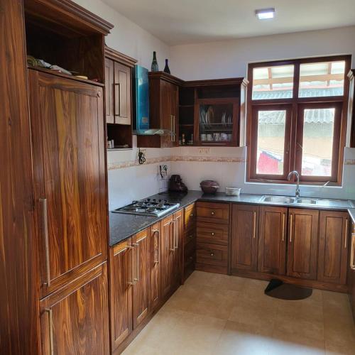 a large kitchen with wooden cabinets and a sink at Quin Villa in Katukurunda-Kalutara