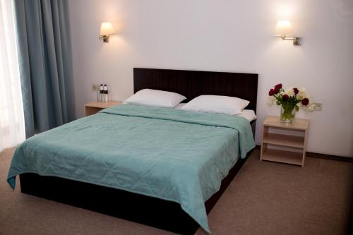 a bedroom with a bed with a vase of flowers on it at Ostrov River Club in Novosëlovka