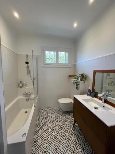une salle de bain avec une baignoire, des toilettes et un lavabo dans l'établissement Maison avec piscine à SEIGNOSSE 8 personnes, à Seignosse