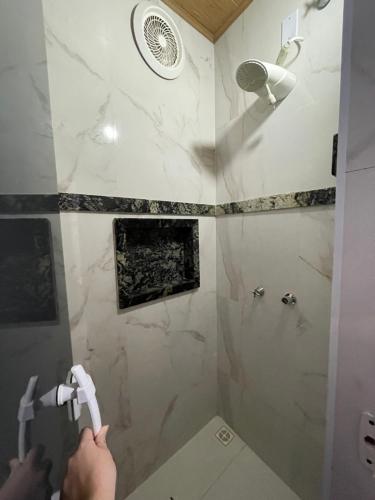 a bathroom with a shower with a person holding a toothbrush at Hospedaje MorroSP in Morro de São Paulo