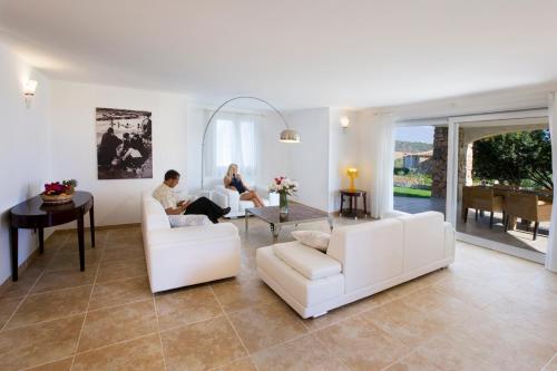 Dos personas están sentadas en una sala de estar. en Villas Resort Wellness & SPA, en Castiadas