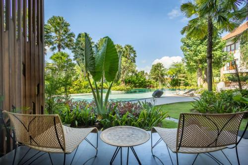 a patio with chairs and a table and a pool at Sanctoo Suites & Villas in Gianyar