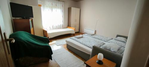 1 dormitorio con cama, sofá y TV en Mura Völgye Vendégház en Murarátka