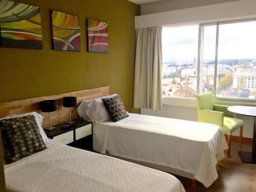 Habitación de hotel con 2 camas y ventana en Center Suites Bariloche en San Carlos de Bariloche