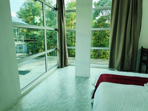 a bedroom with a bed and large windows at NaVita Lodge in Tamparuli