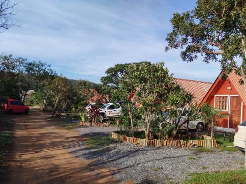 een huis met auto's geparkeerd aan de kant van een onverharde weg bij Pousada Cabanas in Alto Paraíso de Goiás