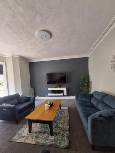 a living room with two blue couches and a coffee table at No 27 Chapel Street Guest House in Llandudno