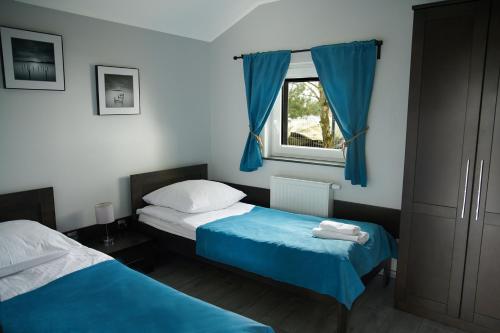 a bedroom with two beds and a window with blue curtains at Jastrzębia Port in Jastrzębia Góra