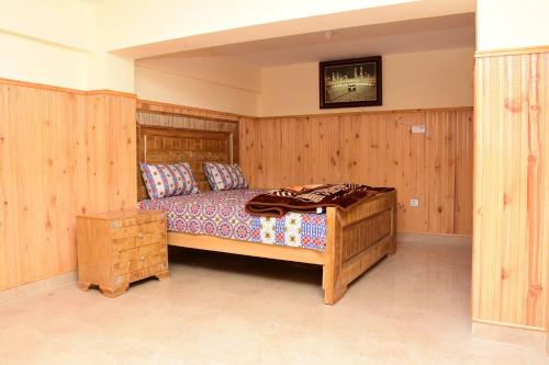 1 dormitorio con 1 cama grande y paredes de madera en Quality Inn Hotel en Murree
