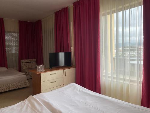 1 dormitorio con 1 cama, TV y cortinas en Hotel Atol, en Sunny Beach
