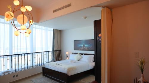 1 dormitorio con 1 cama y balcón con lámpara de araña. en Galaxy Studio Apartment Al reem, en Abu Dabi