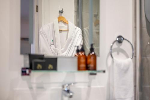 a white robe hanging in front of a bathroom mirror at Exclusive New City Center Designer Mews Home in Chester