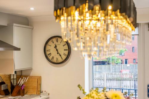 a clock on the wall next to a chandelier at Exclusive New City Center Designer Mews Home in Chester