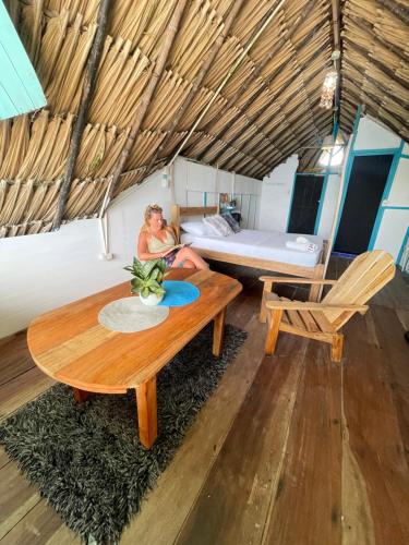 a woman sitting in a room with a table and a bed at Palenque Beach House in San Onofre