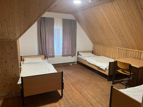 a room with two beds and a table and a window at Waldschlösschen Ricklingen in Hannover