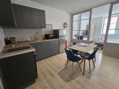 - une cuisine avec une table et des chaises bleues dans la chambre dans l'établissement Appartement au calme idéalement placé à Mâcon., à Mâcon