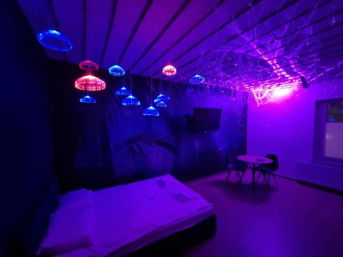 Pokój z fioletowymi lampkami, łóżkiem i stołem w obiekcie Jacuzzi Katowice - Avatar w mieście Katowice