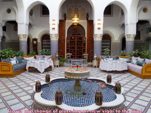Habitación grande con mesas y una fuente en el medio. en Riad El Yacout, en Fez