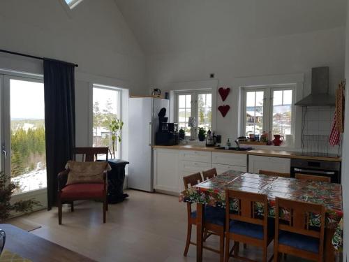a kitchen with a table and some chairs and windows at Villa Fjara in Ulven