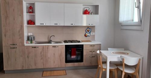 a kitchen with white cabinets and a sink and a table at 27 Via Agricola in Pozzallo