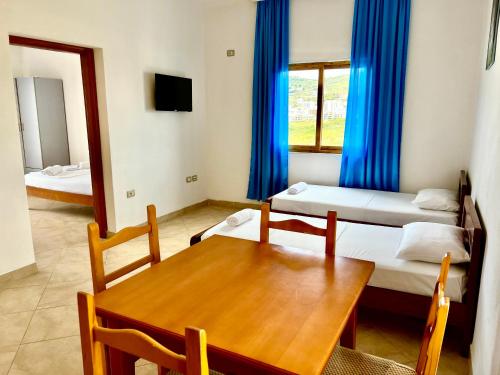 a room with two beds and a table and a mirror at Redi's Seaview Apartments in Sarandë