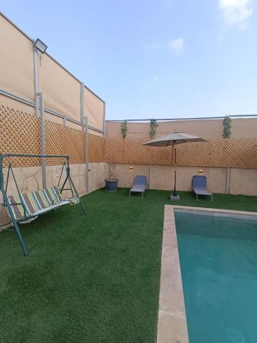 einen Pool mit 2 Stühlen und einem Sonnenschirm in der Unterkunft Airport house in Amman