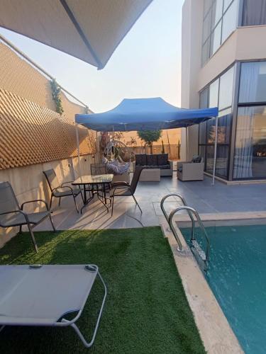 un patio con mesa, sillas y sombrilla azul en Airport house en Amán