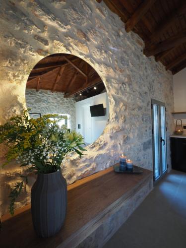 a vase with flowers in a room with a stone wall at Sophia Town Square Areopoli in Areopolis