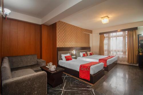 ガントクにあるPalri Boutique Hotelのベッド2台とソファがあるホテルの部屋