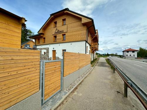 a building with a wooden fence next to a road at Apartmán na Hůrce in Horní Planá