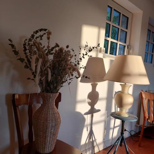 un vase avec des fleurs sur une table à côté de deux lampes dans l'établissement L'Avancée, à Wimille