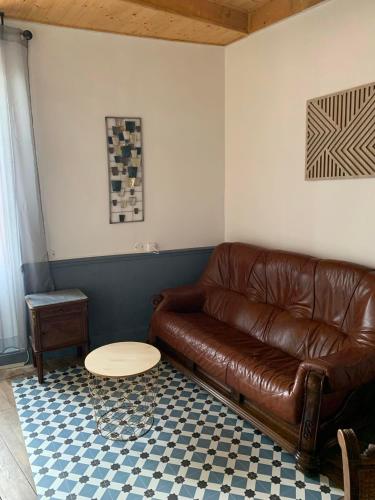 a brown leather couch in a living room with a table at La Muséenne in Mussy-sur-Seine